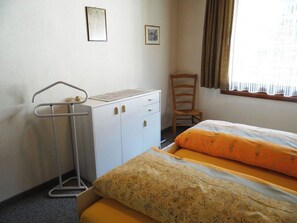 A bedroom with two beds, a desk, a chair, and a window with curtains.