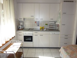 A compact kitchen with white cabinets, a dishwasher, an oven, and a sink.