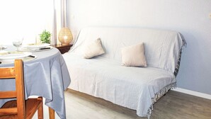 Une pièce confortable avec un lit, une table à manger dressée avec des assiettes et des couverts, une lampe et un panneau accroché au mur.