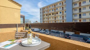 Un balcon avec une table dressée pour deux personnes, une bouteille de vin et un plateau avec des verres.