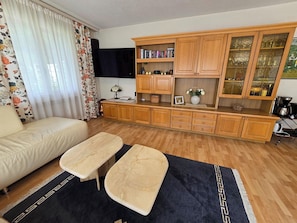 Een woonkamer met een bank, een salontafel, houten kasten en een televisie.