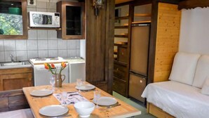 A compact kitchen with a dining area, a wooden table set for four, and a white sofa. - Grand Roc by Interhome (Argentière)