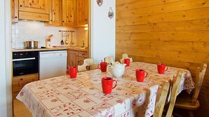 A cozy kitchen with wooden cabinets, a dishwasher, and a dining table set with red cups and a white pitcher.