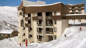A multi-story hotel with balconies, situated in a snowy mountainous area.