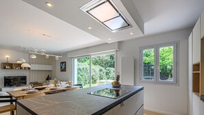 A modern kitchen with a large island, built-in appliances, and large windows offering a view of the outdoors. - Les Marines by Interhome (Carnac)