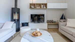 A modern living room with a fireplace, sofa, TV, and decorative items. - Les Marines by Interhome (Carnac)