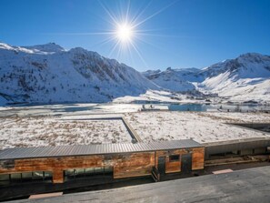 A modern building with a flat roof, surrounded by snow-covered mountains and a clear sky. - Les Cimes (Le Lac) by Interhome (Tignes)