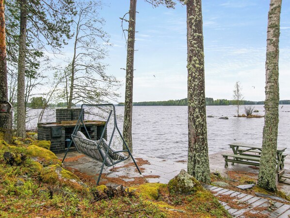 A lakeside cabin with a swing chair and picnic table.