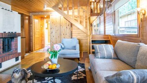 A cozy wooden interior with a fireplace, a sofa, a chair, and a dining table with fruit. - Tipuniemi by Interhome (Hämeenlinna)