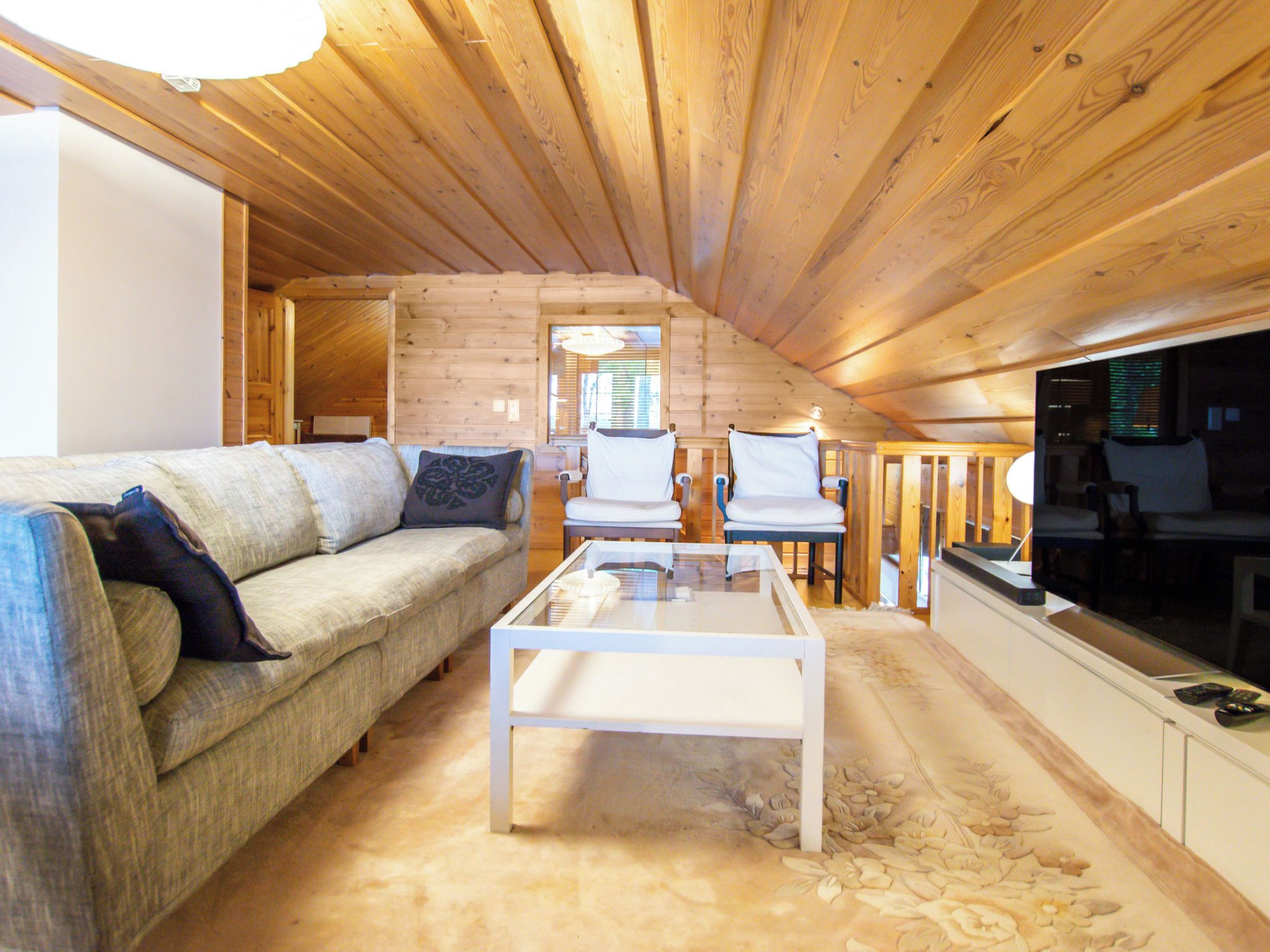 L’intérieur d’un chalet confortable, avec une cheminée, un canapé, une table basse en verre et un téléviseur.