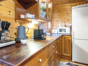 Una cocina de madera con cafetera, microondas y refrigerador.