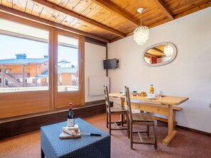 Un comedor de madera con una mesa, sillas, una botella de vino y un espejo en la pared.