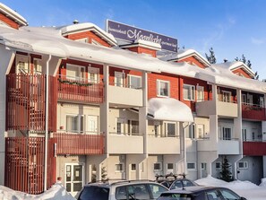 Un hotel de varios pisos con balcones, un letrero que indica que es un hotel-apartamento Moonlight y automóviles estacionados al frente.