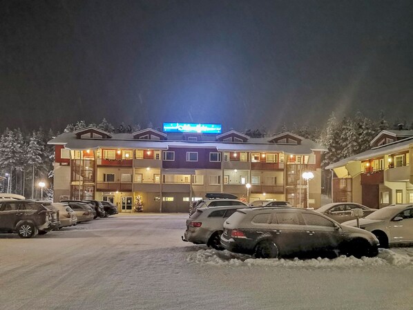 A multi-story hotel with a snow-covered parking lot and illuminated signage. - Levin tuisku by Interhome (Kittilä)