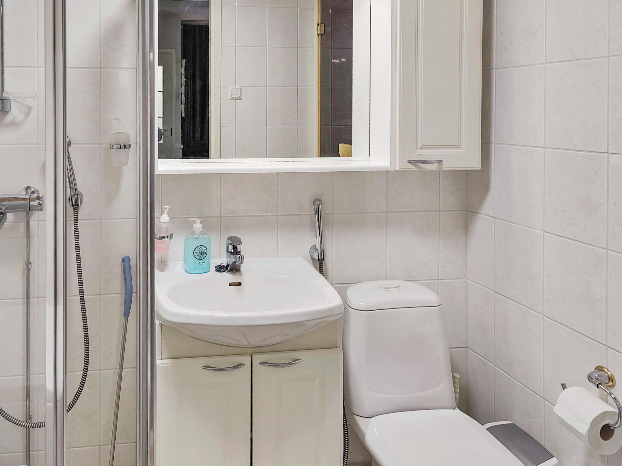 A bathroom with a shower, sink, toilet, and a mirror above the sink.