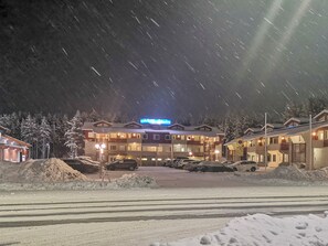 Un hotel de varios pisos, un estacionamiento y alrededores cubiertos de nieve.
