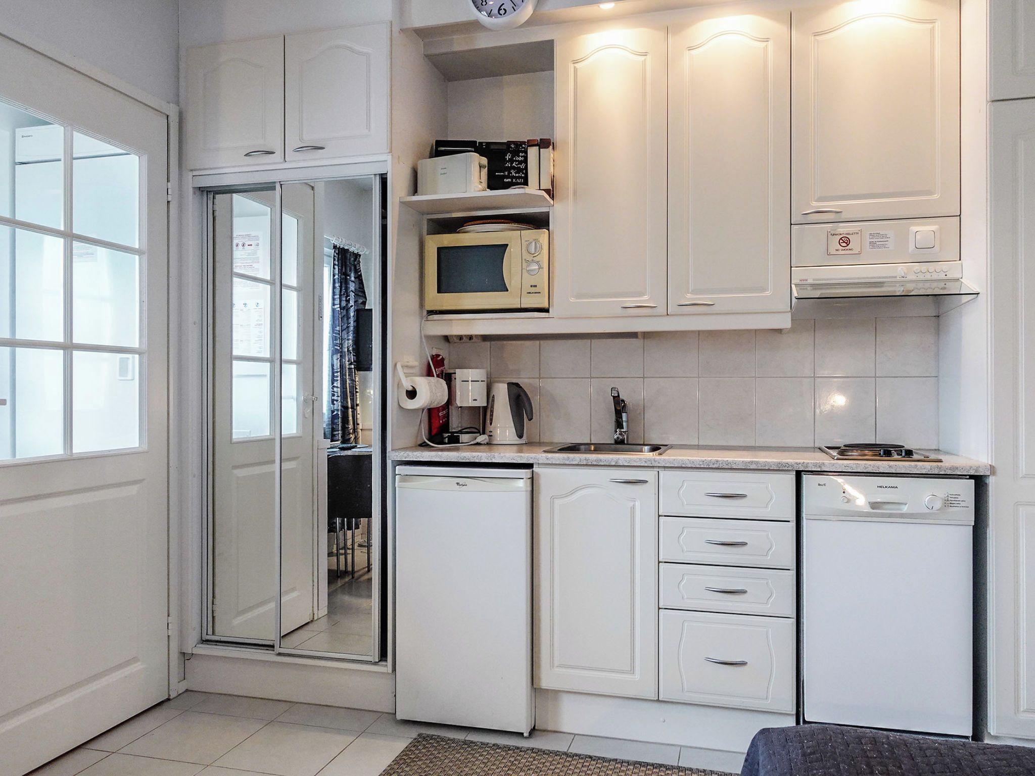 A compact kitchen with white cabinets, a microwave, a coffee maker, and a dishwasher.