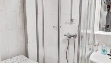 A bathroom with a glass-enclosed shower, a white toilet, and a sink with a mirror above it.