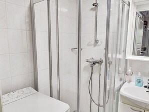 A bathroom with a glass-enclosed shower, a white toilet, and a sink with a mirror above it. - Levin tuisku by Interhome (Kittilä)