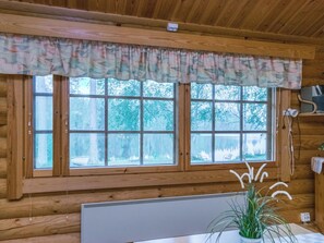 A cabin with a large window, wooden walls, a radiator, and a plant. - Uitonniemi, rummukkala by Interhome (Heinävesi)