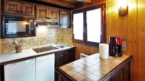 A compact kitchen with wooden cabinets, a microwave, a sink, and a coffee maker. - Pierre Blanche by Interhome (Les Houches)