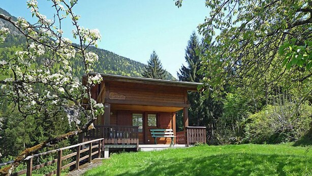 A wooden cabin with a porch and a bench, surrounded by lush greenery and trees. - Pierre Blanche by Interhome (Les Houches)