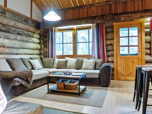 A log cabin interior with a sofa, a coffee table, and a door. - Vuokatinportti a 9 by Interhome (Sotkamo)