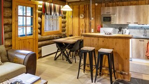 A log cabin interior with a dining area, kitchen, and a cozy seating area.