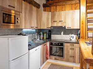 A compact kitchen with wooden cabinets, a built-in oven, a sink, and a refrigerator.