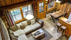 A cozy log cabin interior with a sofa, dining table, and bar area.