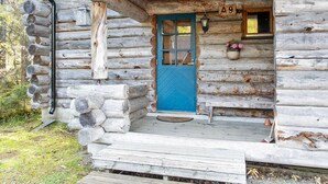 A rustic log cabin with a blue door, numbered 9, and a porch with steps leading to the entrance.