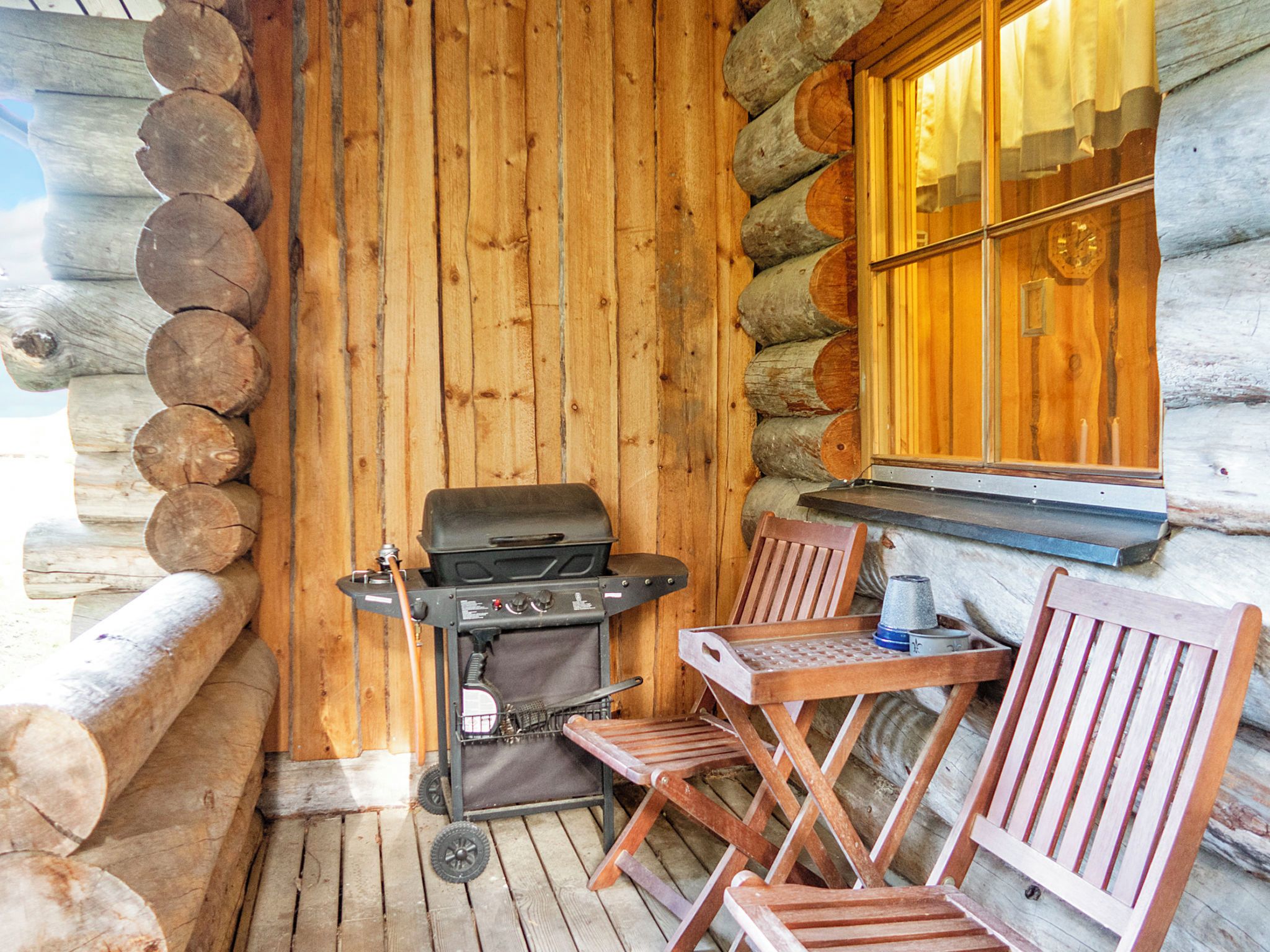 Une cabane en rondins avec un barbecue et un espace salon extérieur.