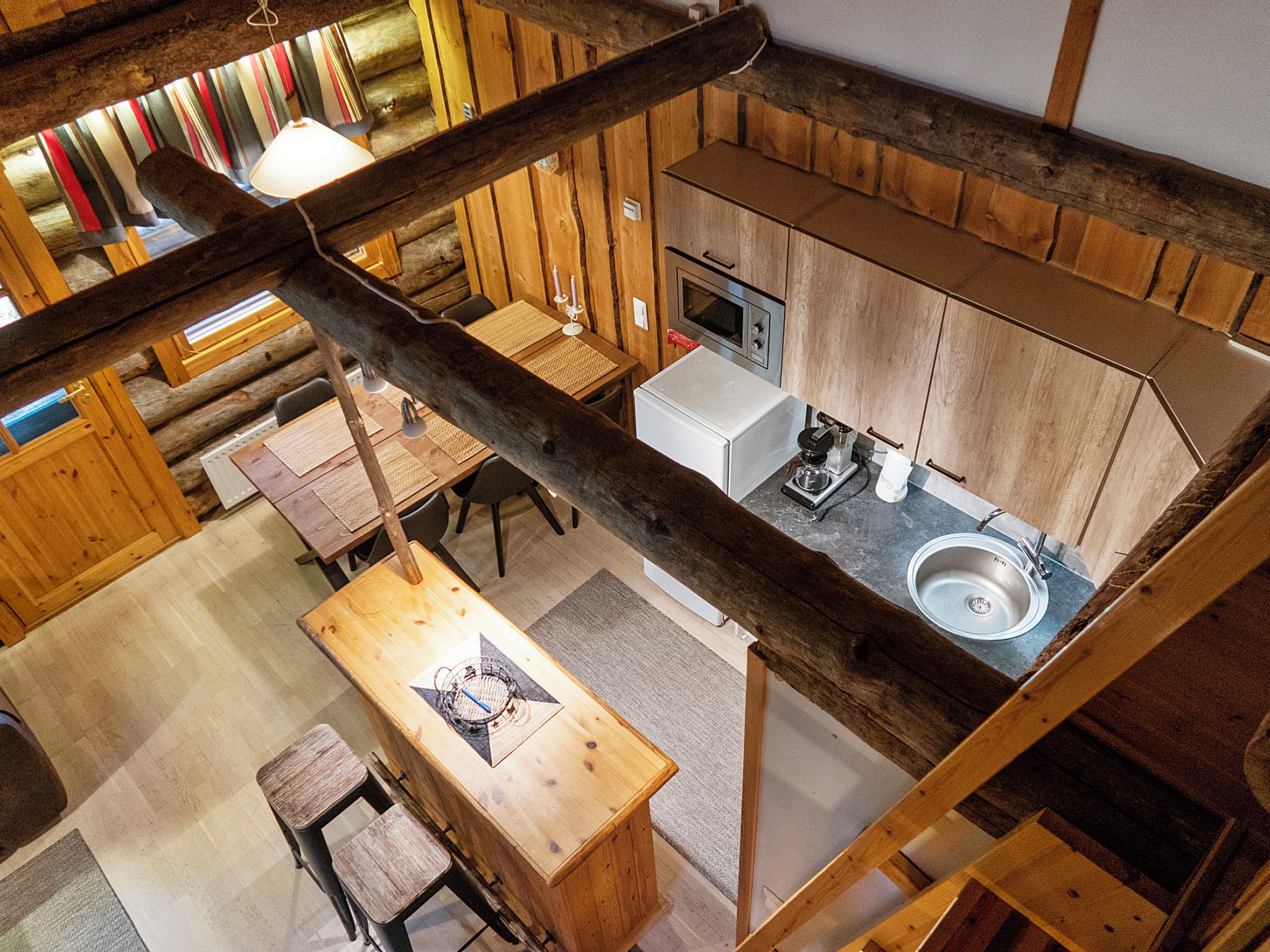 A wooden interior with a kitchen area, a dining table, and a bar.