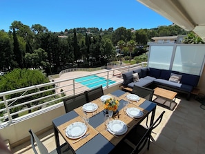 A balcony with a pool, outdoor seating, and a table set for dining.