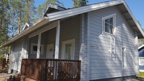 Eine kleine, eingeschossige Holzhütte mit Veranda und einer Holzterrasse.