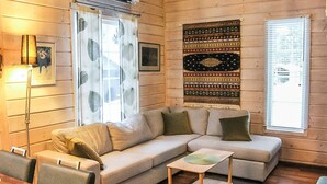 Ein gemütliches Wohnzimmer mit einer Eckcouch, einem kleinen Holztisch und einem gemusterten Teppich.