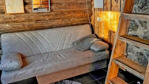 A cozy cabin interior with a sofa, wooden walls, a map, and a small shelf. - Tievatupa 2, pienempi by Interhome (Ylläsjärvi)