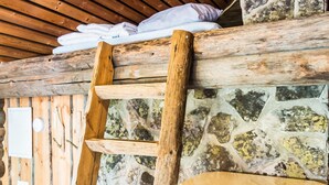 A wooden ladder leaning against a stone wall with a rustic wooden ceiling and a white cabinet below. - Tievatupa 2, pienempi by Interhome (Ylläsjärvi)