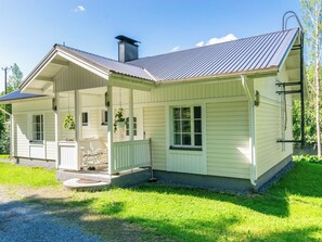 Una casa a un piano con veranda, un camino e un prato curato.