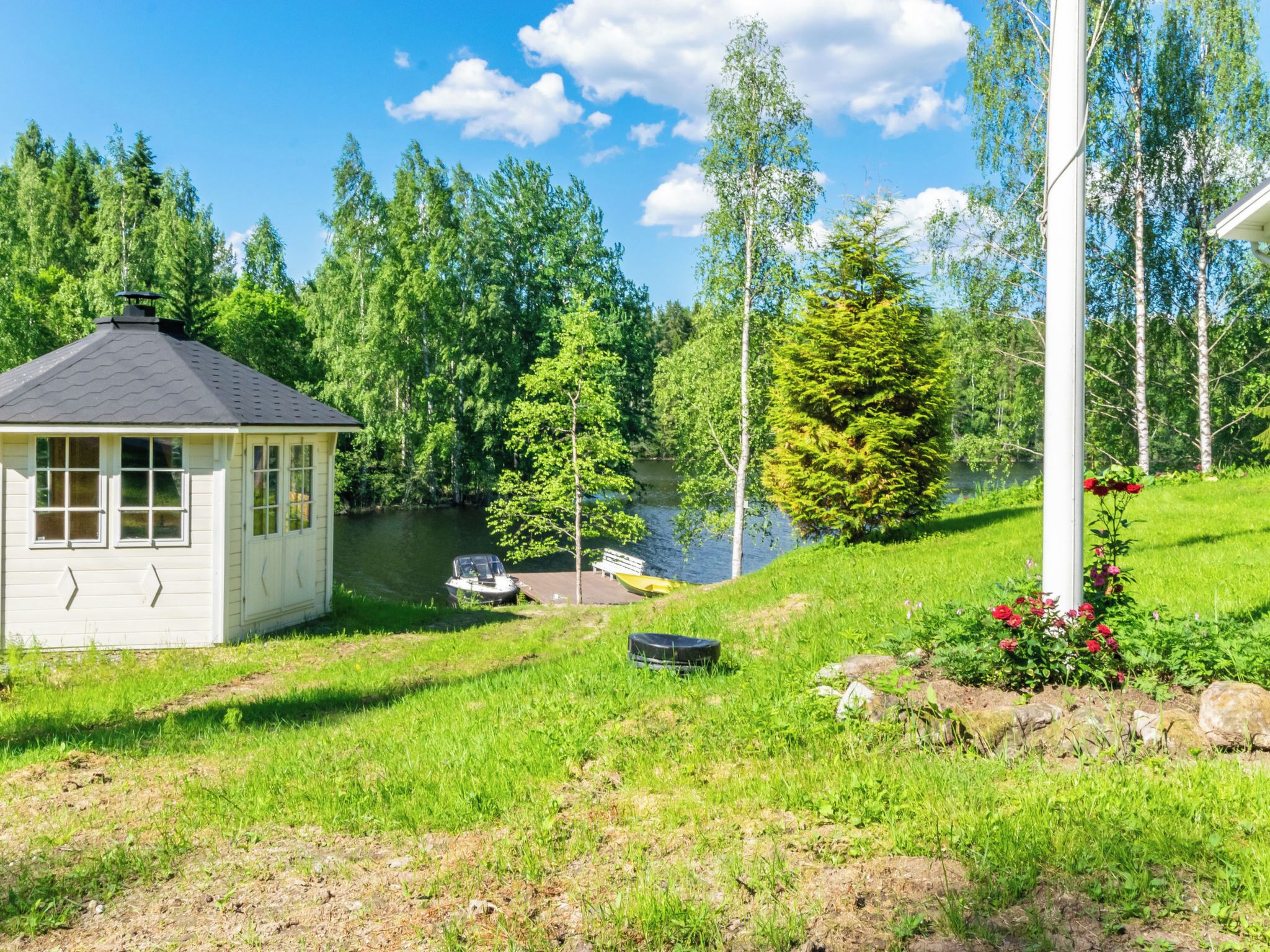 A lakeside cabin with a dock, surrounded by lush greenery and trees.