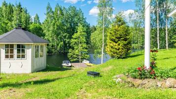 A lakeside cabin with a dock, surrounded by lush greenery and trees.