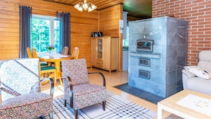 L’intérieur chaleureux d’un chalet avec des murs en bois, un coin repas, une cheminée et un espace détente.
