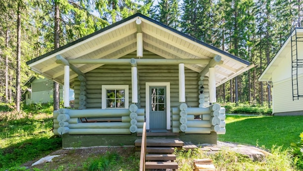 Une cabane en rondins dotée d’une véranda, d’une porte d’entrée et d’un escalier menant à l’étage.