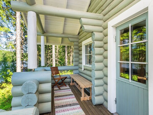 A log cabin with a porch, a bench, and a chair.