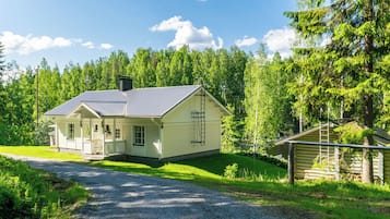 A single-story house with a porch, a chimney, and a small adjacent shed.