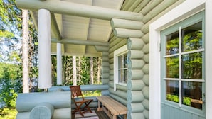 Une cabane en rondins avec une véranda, un banc et une table.