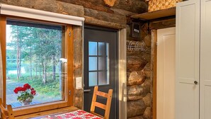 Un banc en bois avec une table, une fenêtre donnant sur des arbres, une porte avec une pancarte et un mur à la texture bois.
