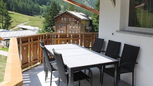 A balcony with a table and chairs, overlooking a mountainous landscape. - Weideli by Interhome (Saas-Grund)
