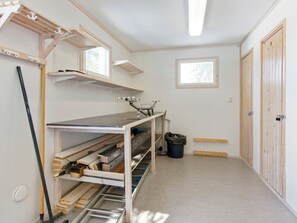 Un couloir étroit avec un établi, des étagères et une porte.