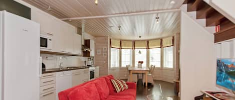 Een moderne keuken met witte kasten, een rode bank en een eethoek met een tafel en stoelen.